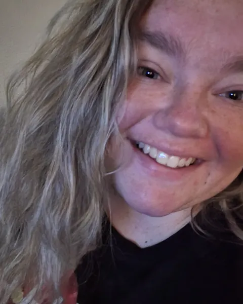 A smiling woman with long wavy hair, a selfie posted on The Hangar Daycare’s Google profile