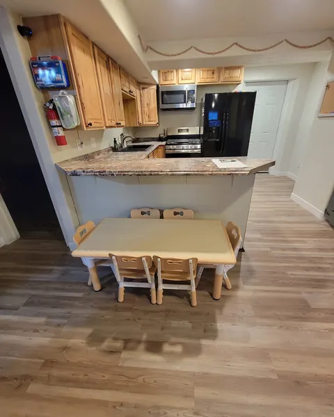 A kitchen with a low kids’ table and small wooden chairs in front of the counter