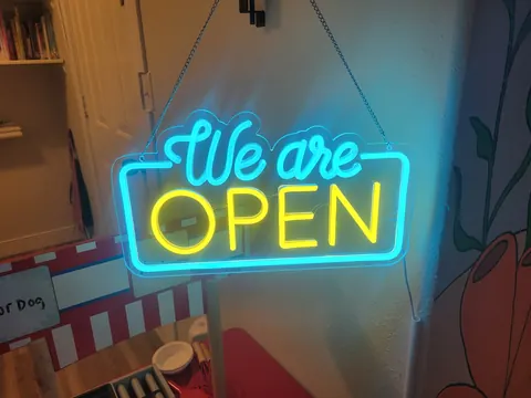 A glowing neon sign that reads We are OPEN