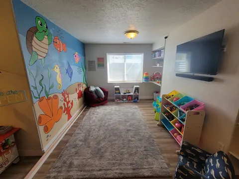 A long playroom with an ocean mural of a sea turtle and fish, toy shelves and a play kitchen