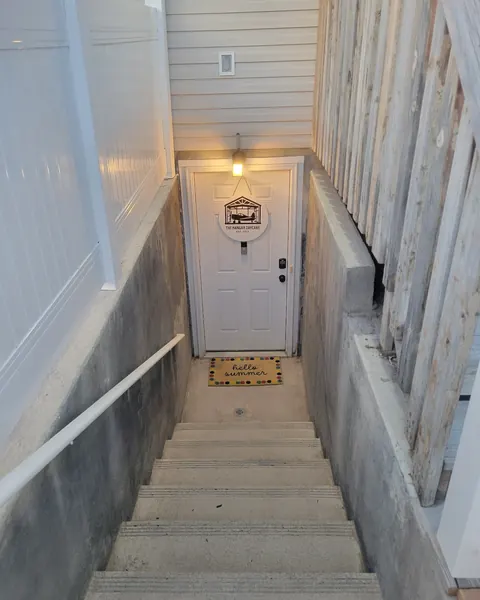 Concrete steps leading down to a white side door with a small sign on it